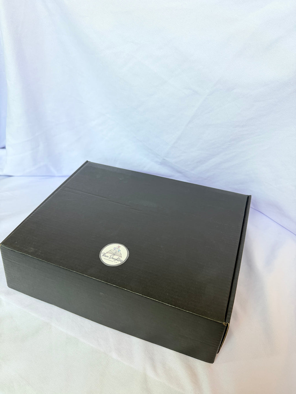 Closed black keepsake gift box with Three Daughters Keepsake Co. logo sticker