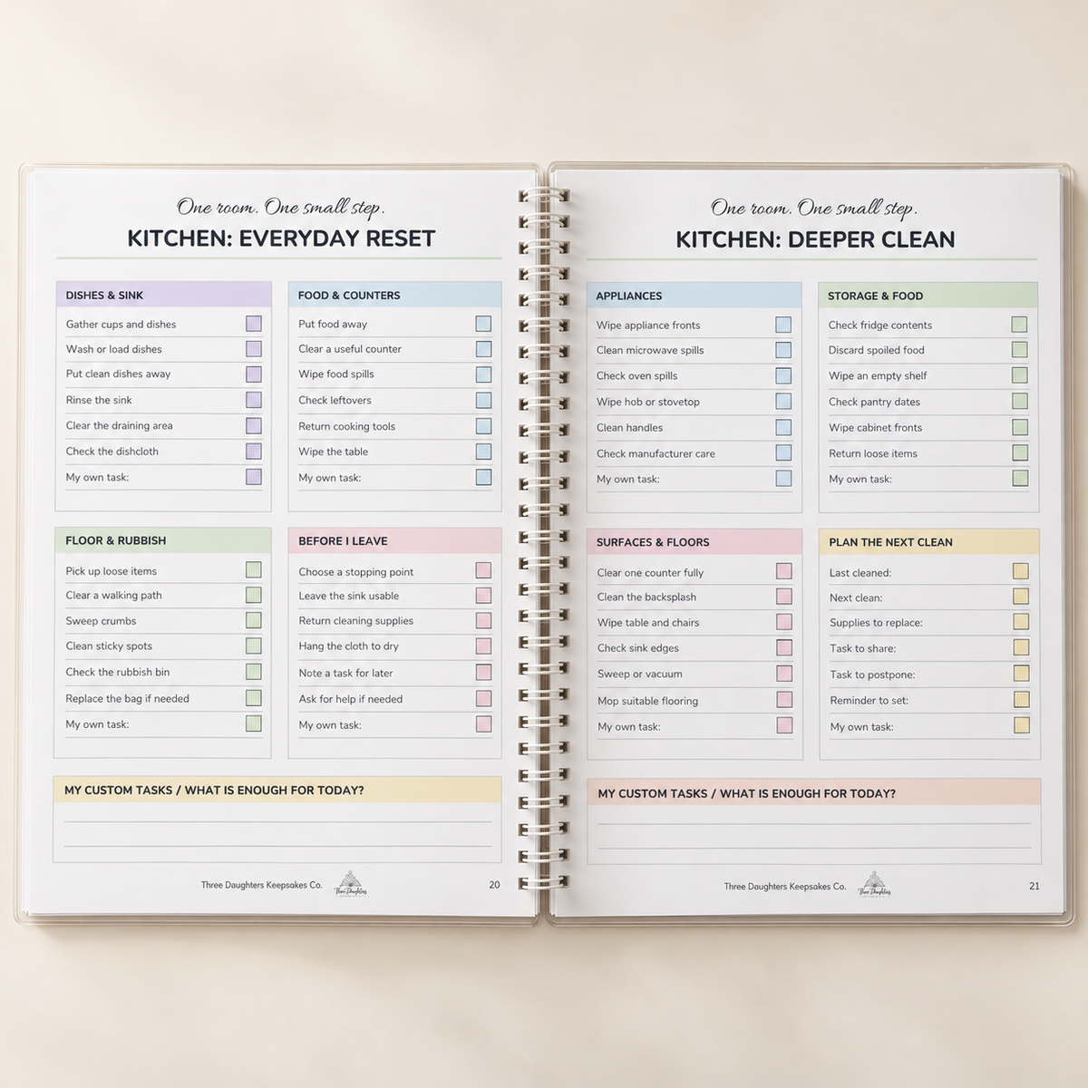 Open spiral cleaning planner showing kitchen everyday reset and kitchen deeper clean checklist pages